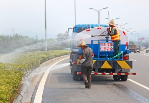 104国道上绿化工人正在为隔离带绿化洒水